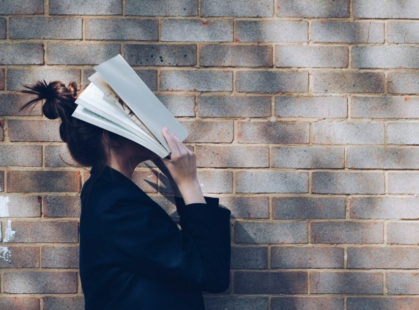 woman covering her face with white book