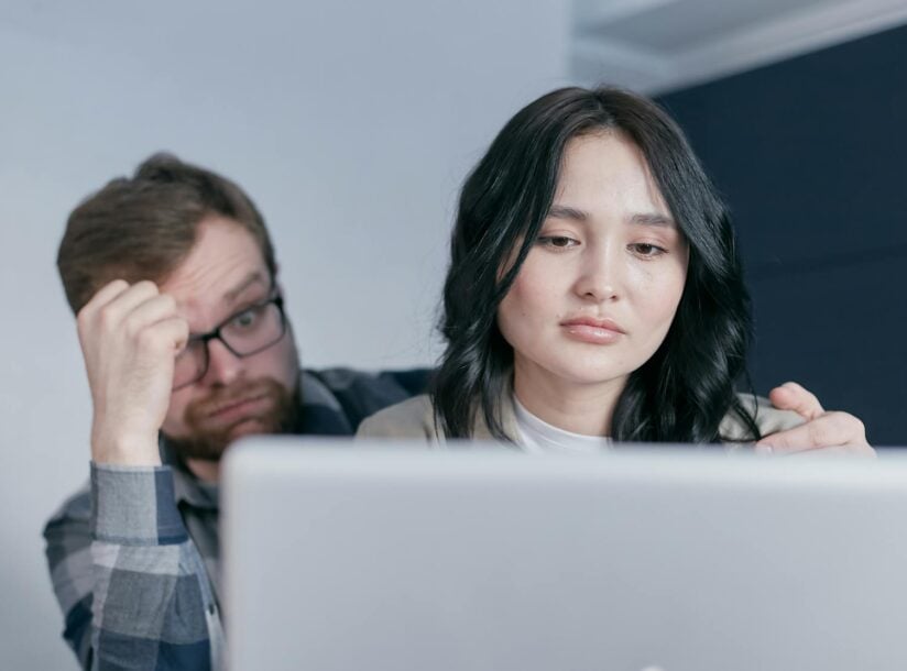 An interracial couple looking worried while checking finances at home.